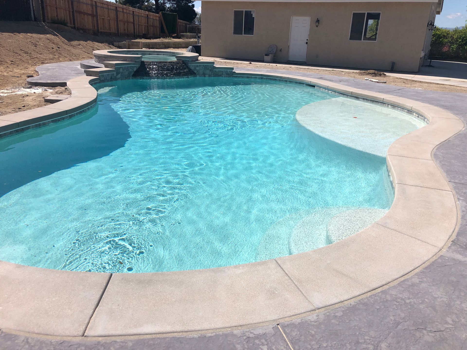 A large swimming pool with a house in the background