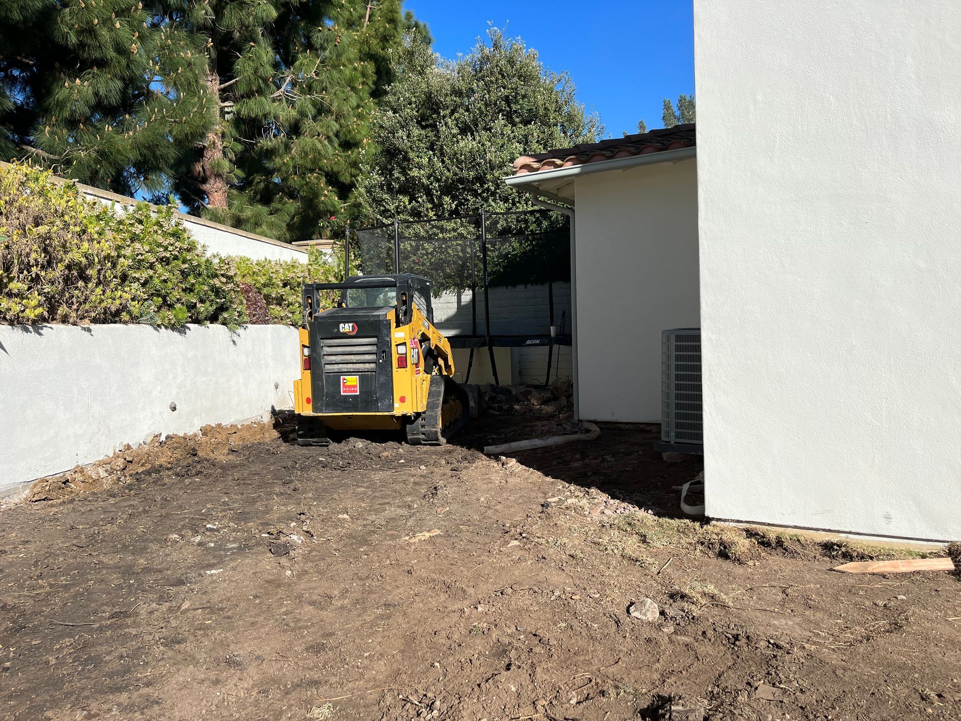 A bulldozer is moving dirt in front of a house.