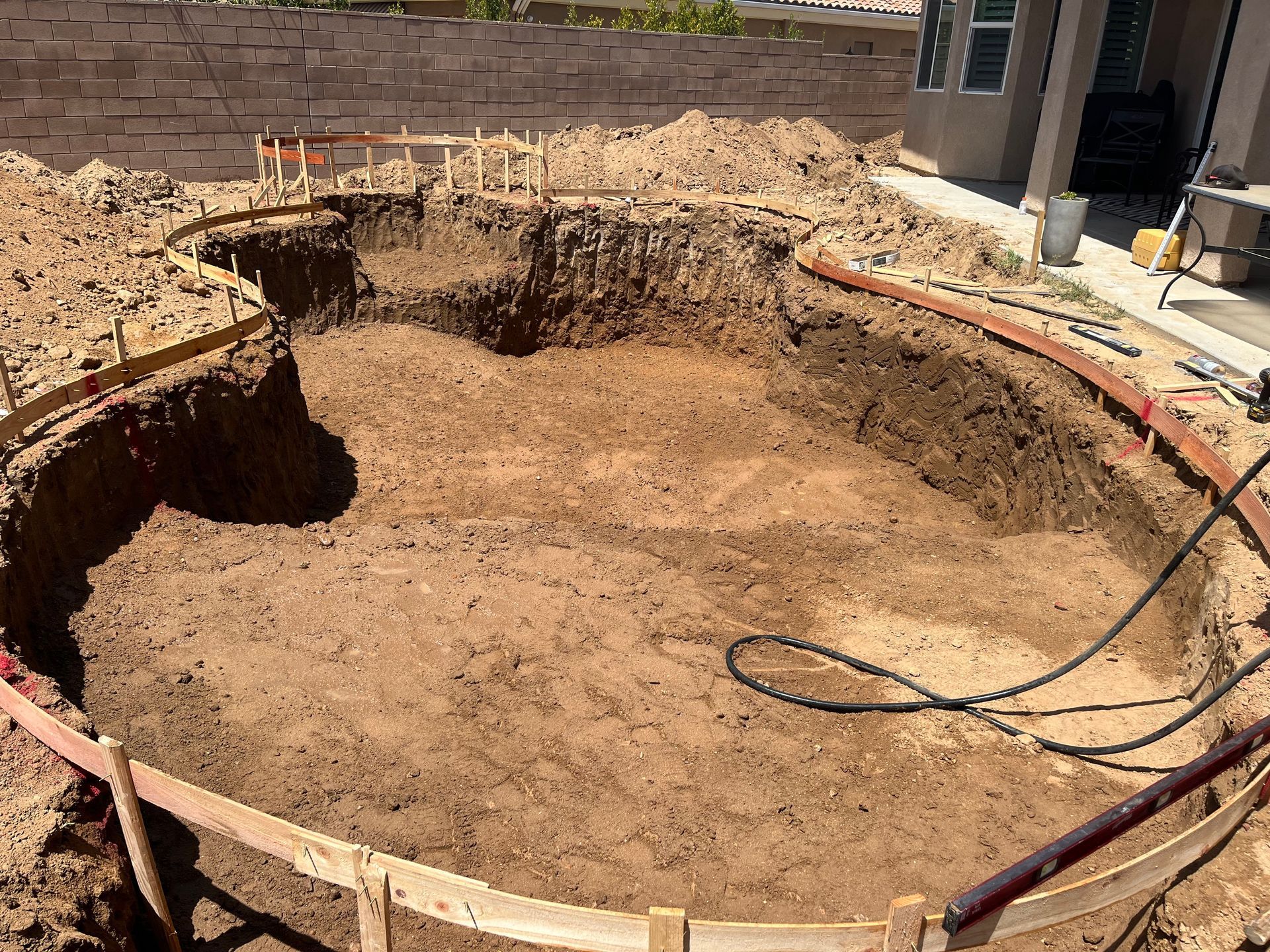 A swimming pool is being built in the backyard of a house.
