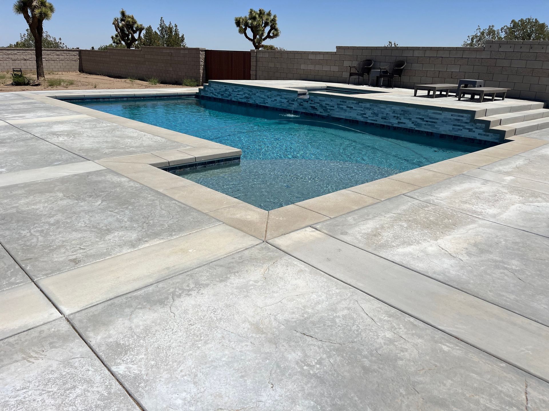 A large swimming pool is surrounded by a concrete patio