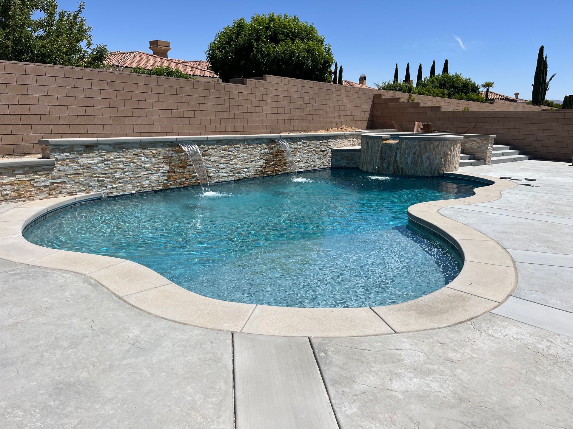A large swimming pool with a waterfall in the backyard
