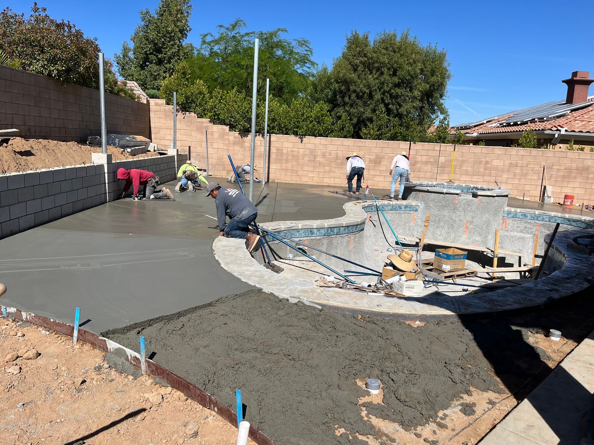 A group of construction workers are working on a swimming pool.