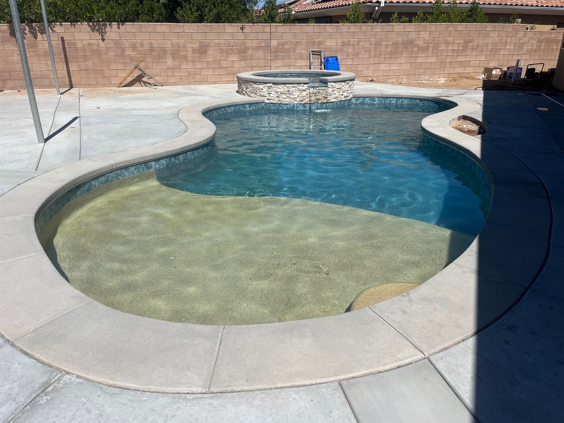 A large swimming pool with a brick wall in the background