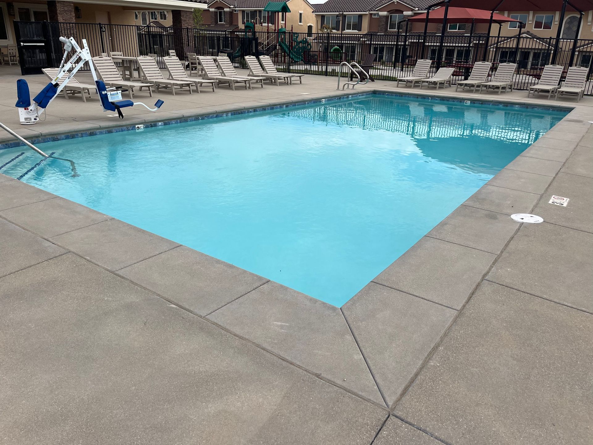 A large swimming pool surrounded by chairs and umbrellas.