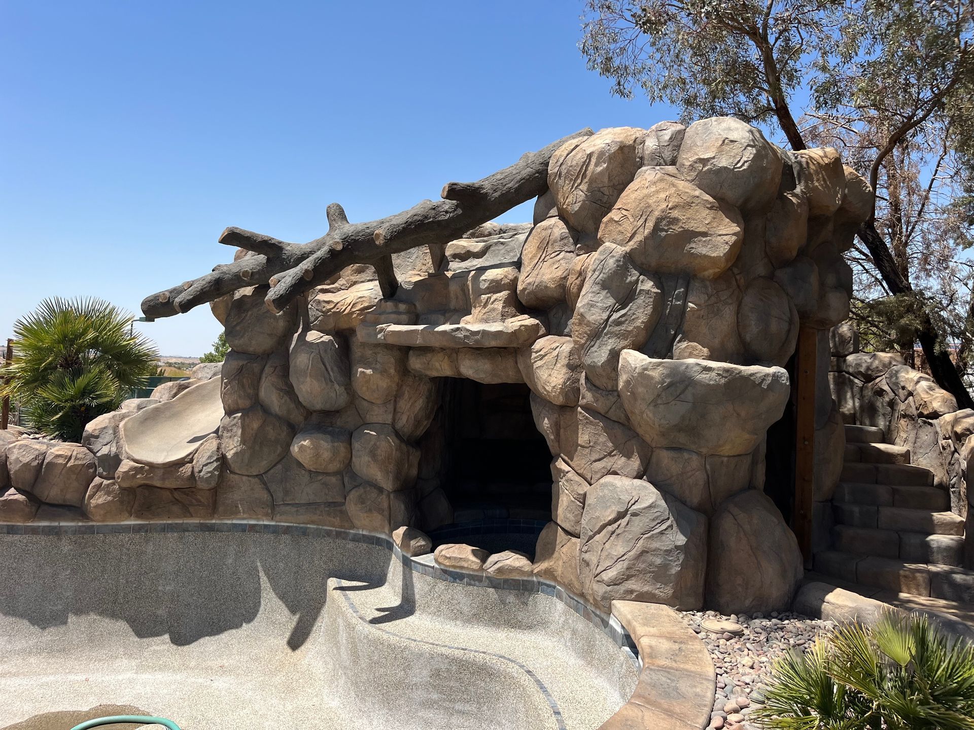 A cave made of rocks next to a pool