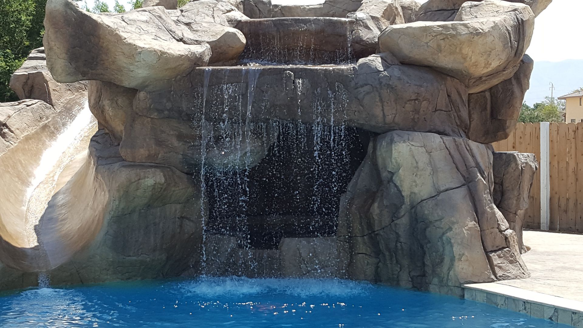 A waterfall is surrounded by rocks and a swimming pool