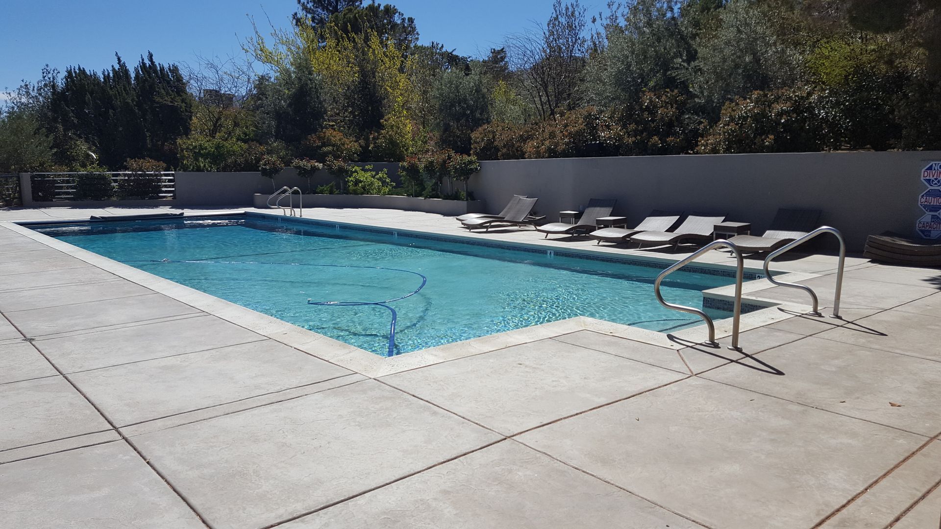 A large swimming pool surrounded by chairs on a sunny day
