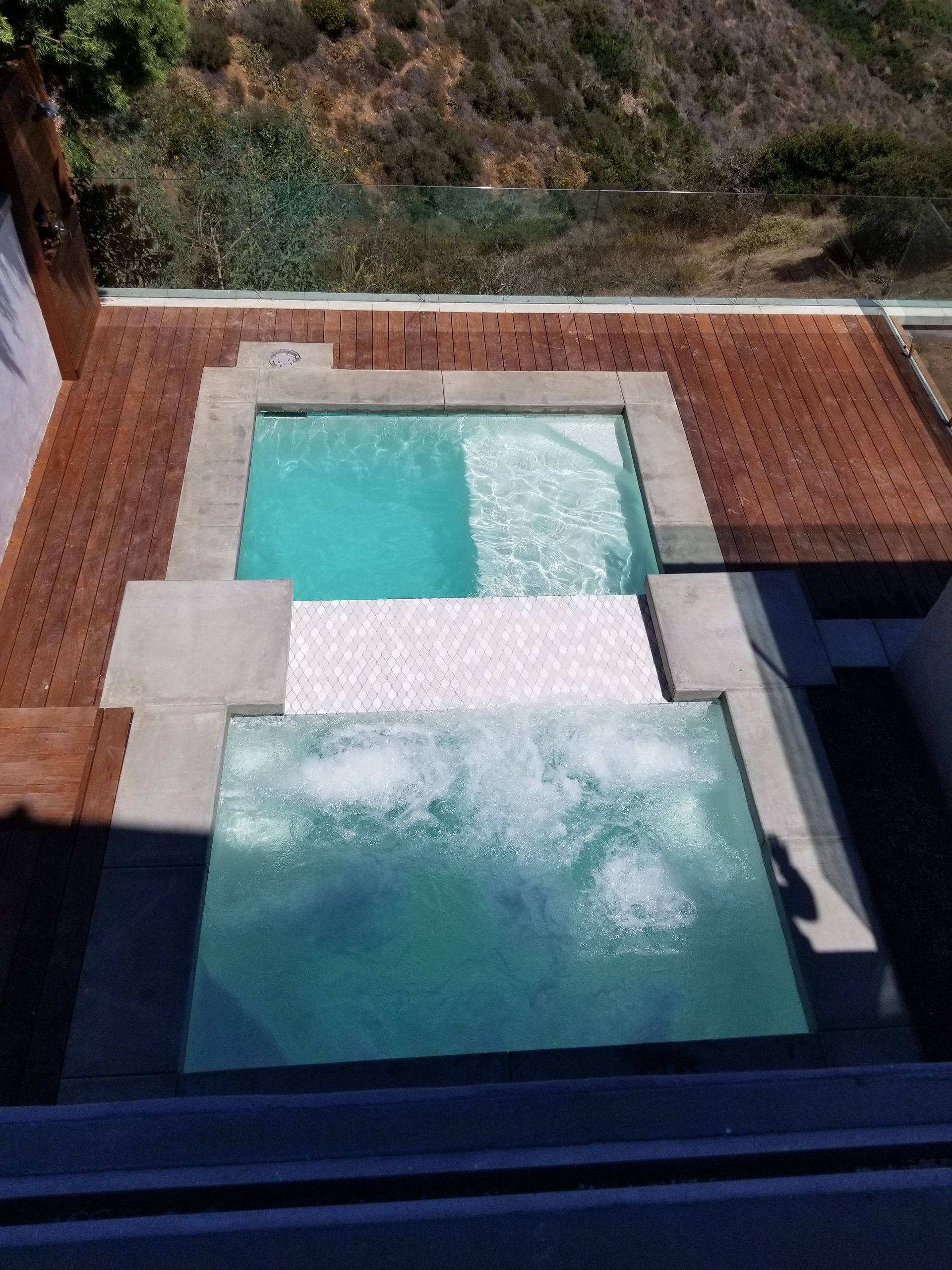 A large swimming pool is surrounded by a wooden deck.