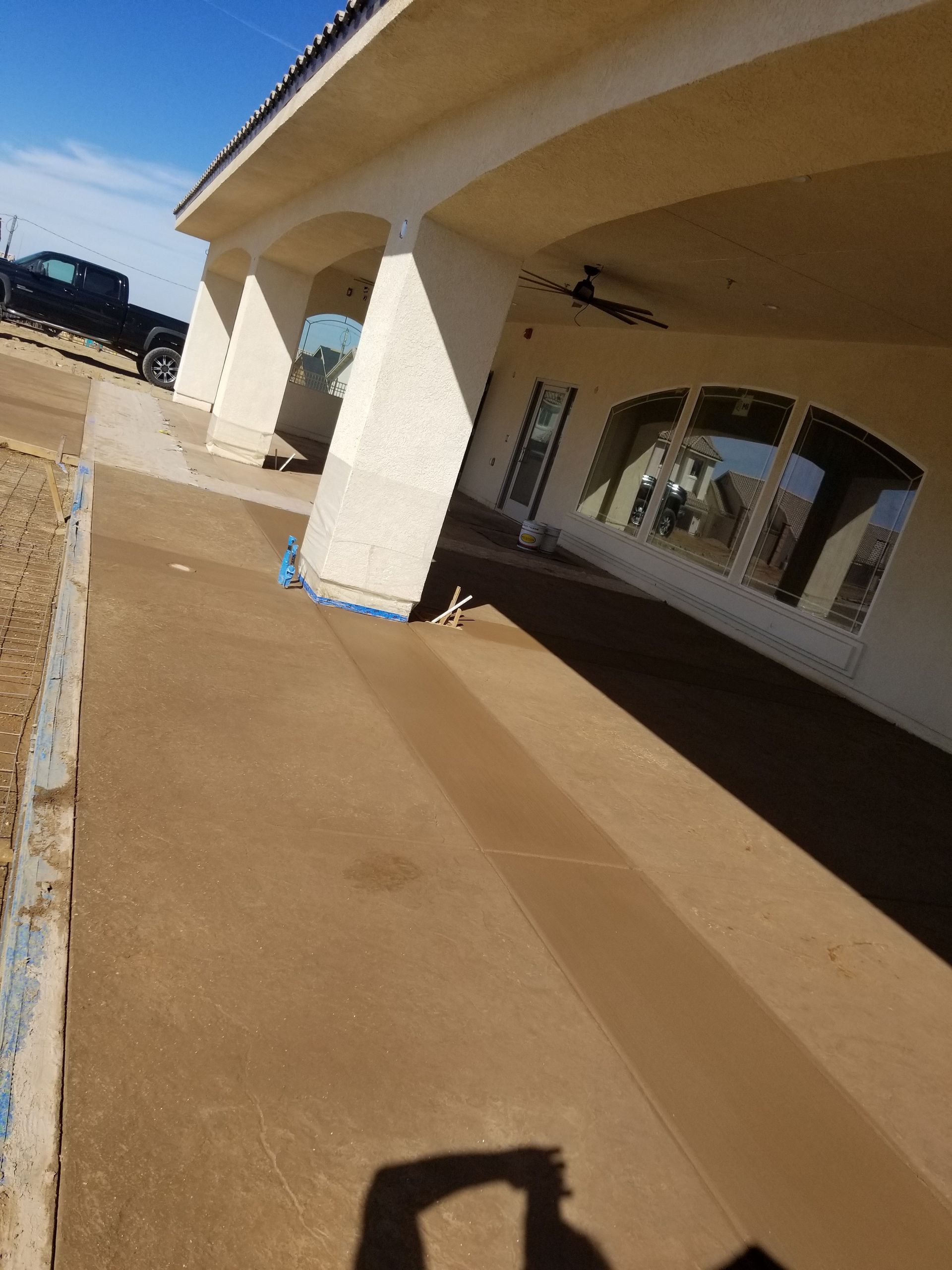 A shadow of a person is cast on the sidewalk in front of a building.