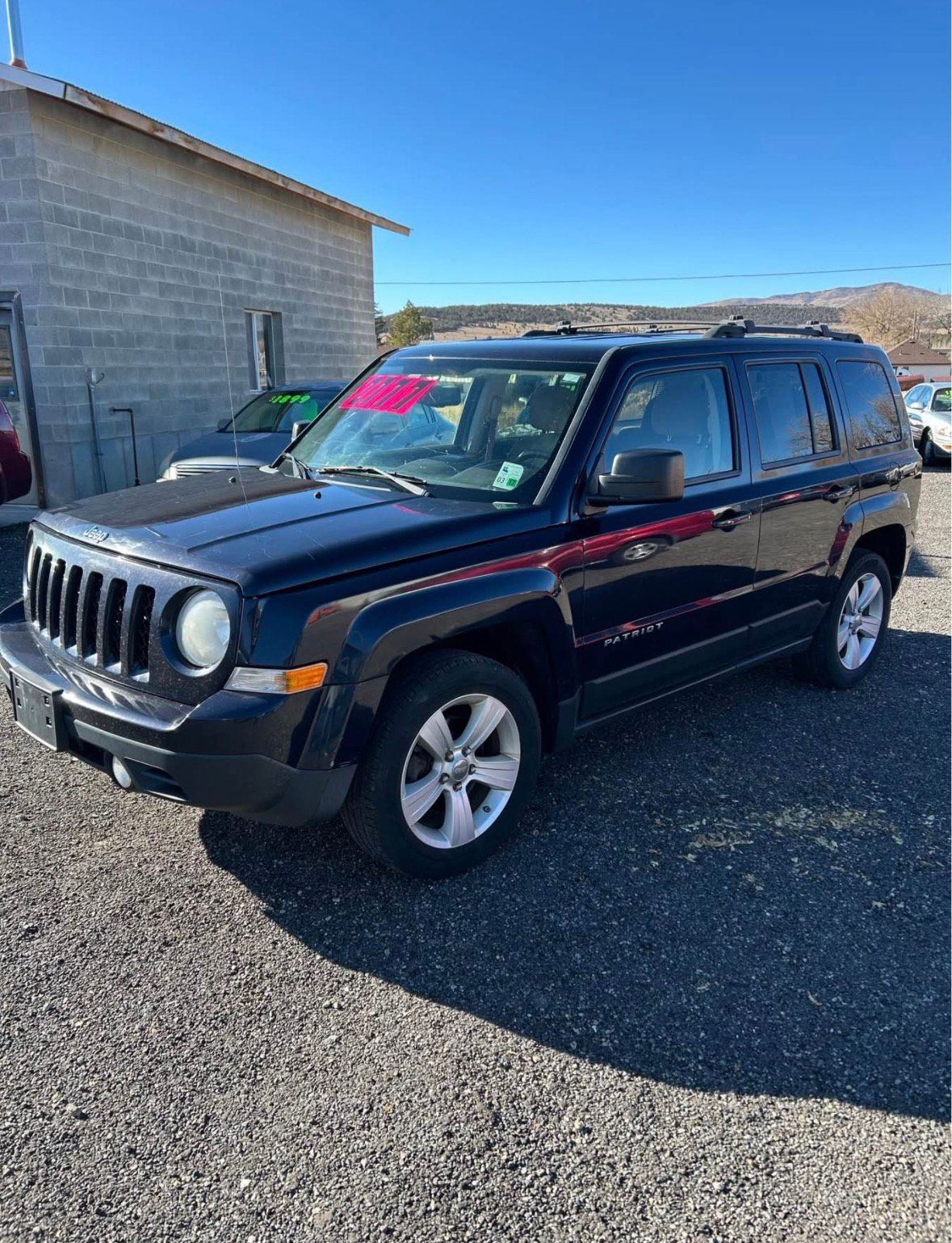 Black Jeep Patriot parked outside on a sunny day.