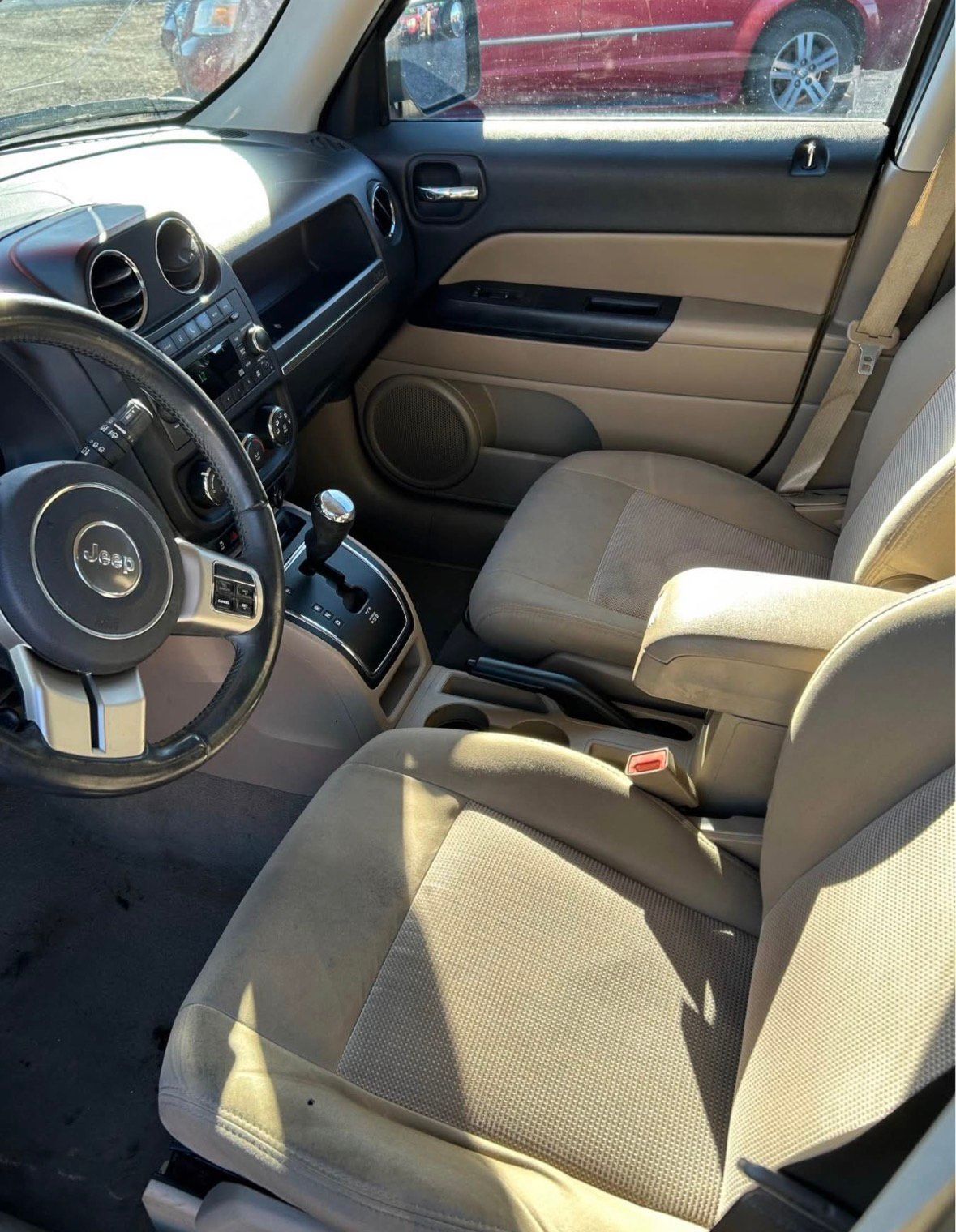 Interior of a Jeep Patriot, tan seats, black dashboard, steering wheel visible.