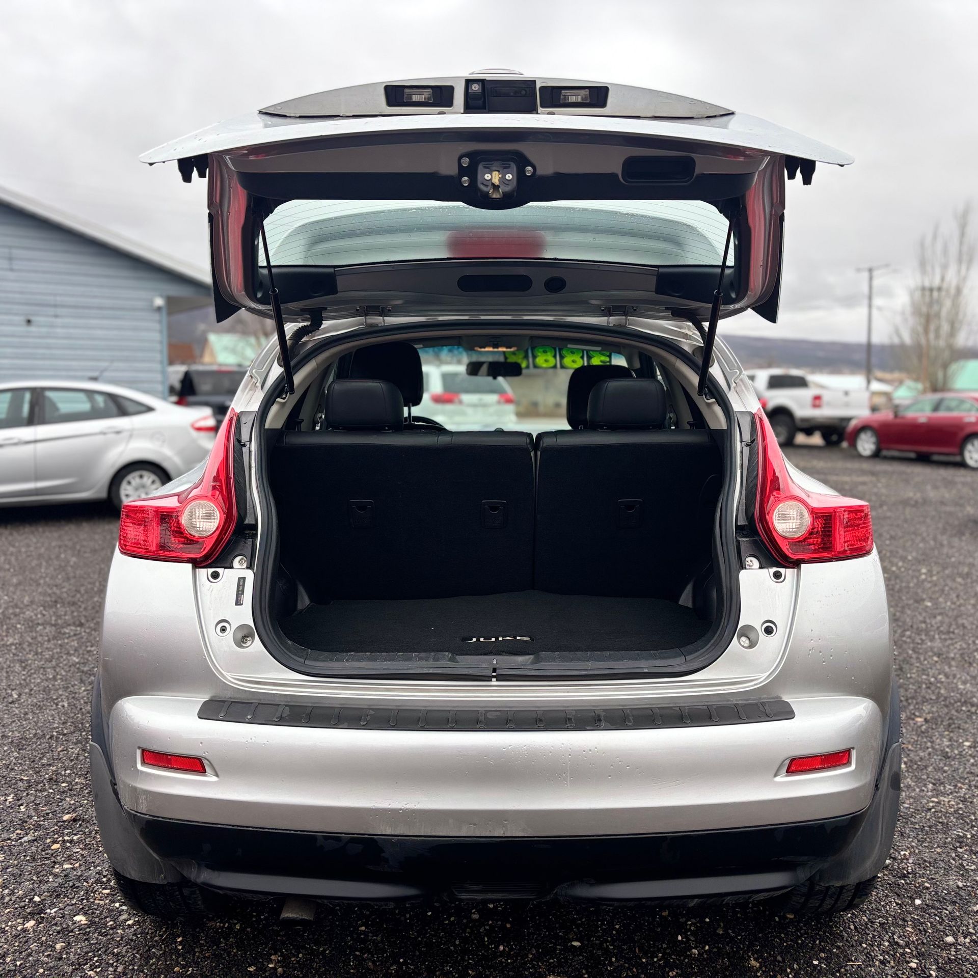 Silver SUV with open trunk at a car dealership.