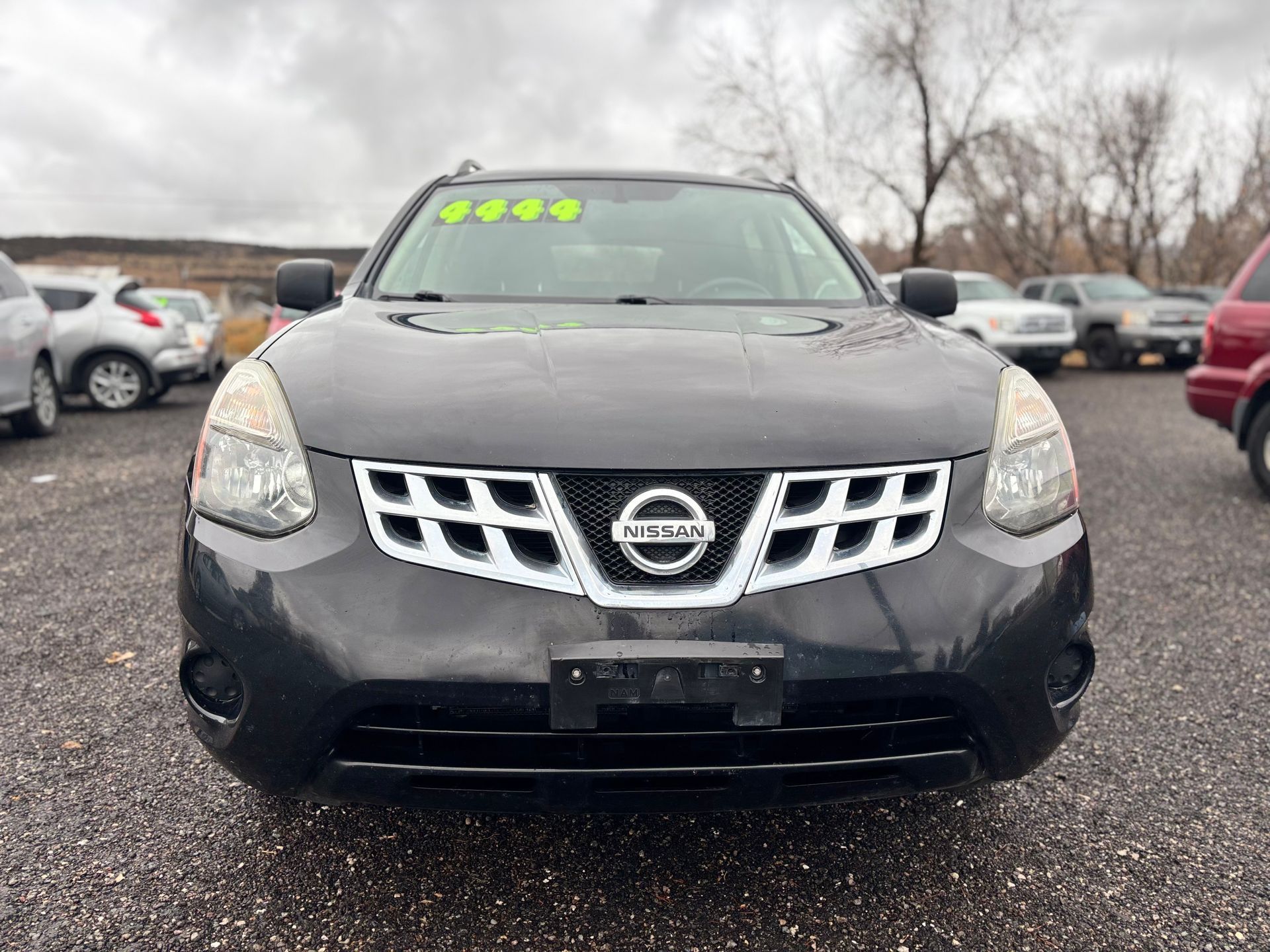 Black Nissan Rogue SUV in a car lot on an overcast day.