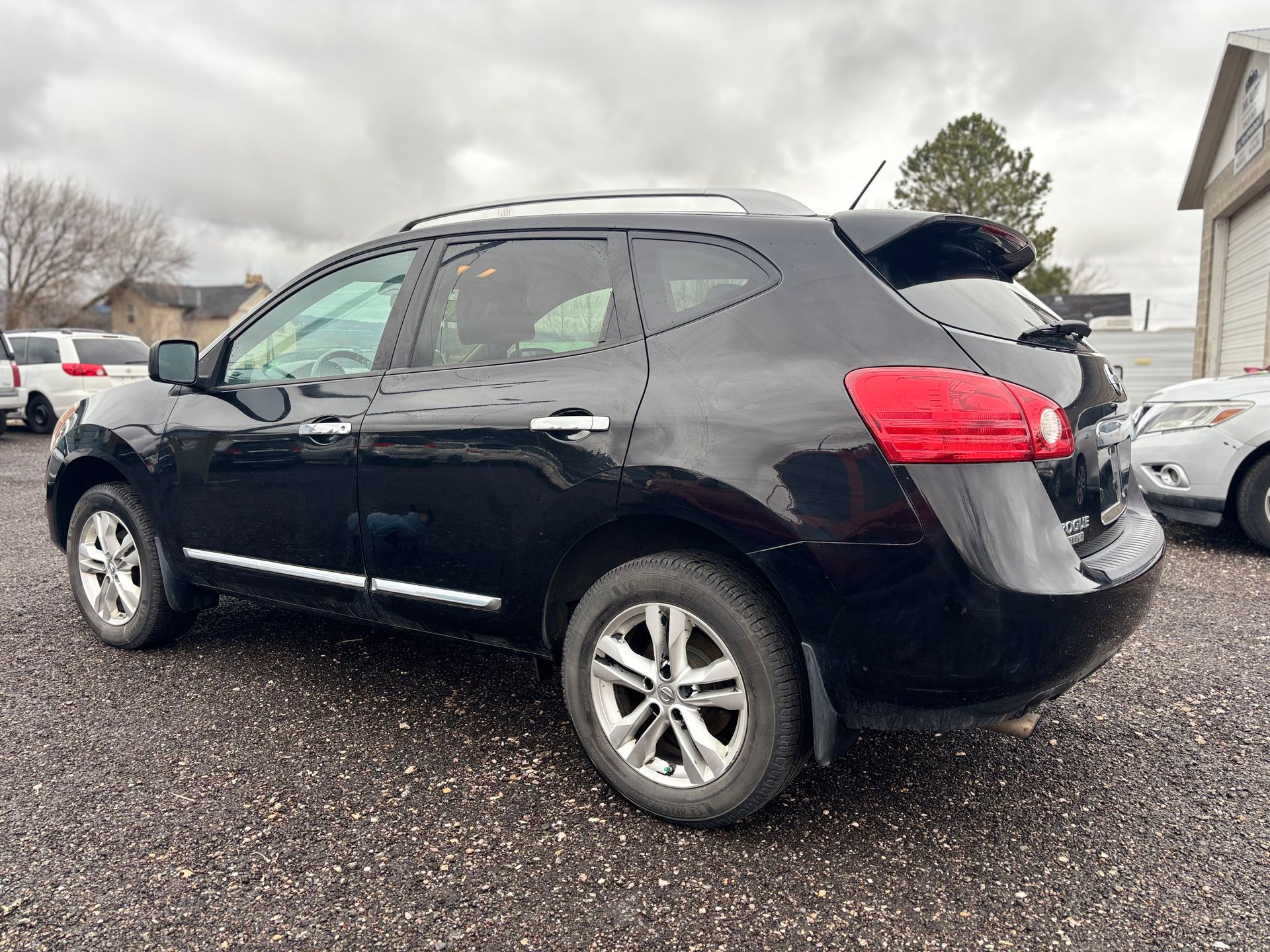 Black Nissan Rogue SUV parked on gravel lot.
