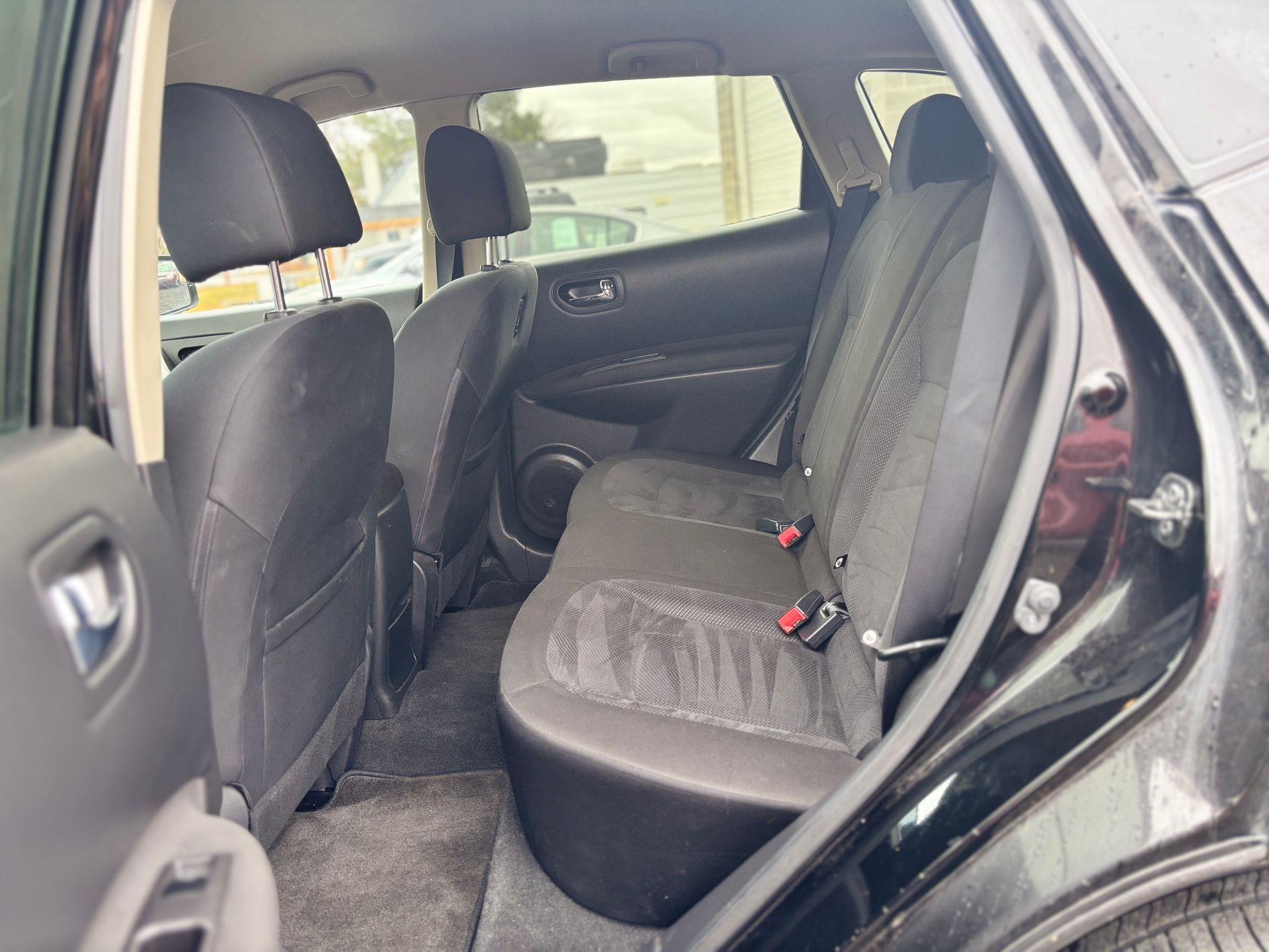 Interior of a black SUV with rear seats visible, showing headrests, seatbelts, and a window.