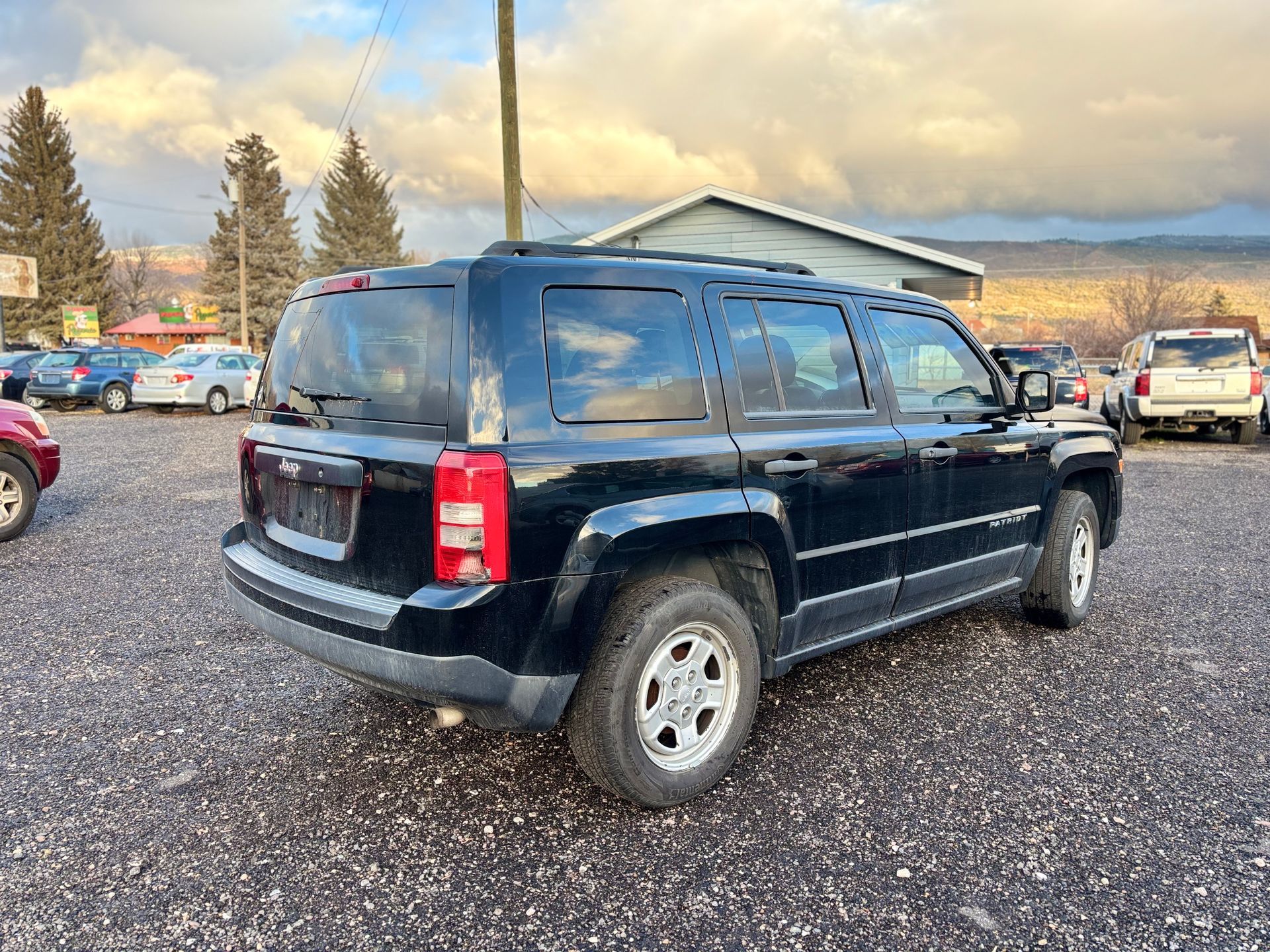 Black Jeep Patriot SUV parked outside on a cloudy day.