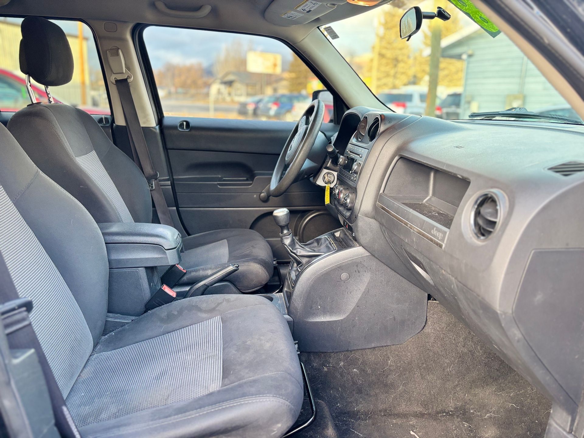 Interior of a black Jeep Patriot, showing seats, dashboard, and steering wheel.