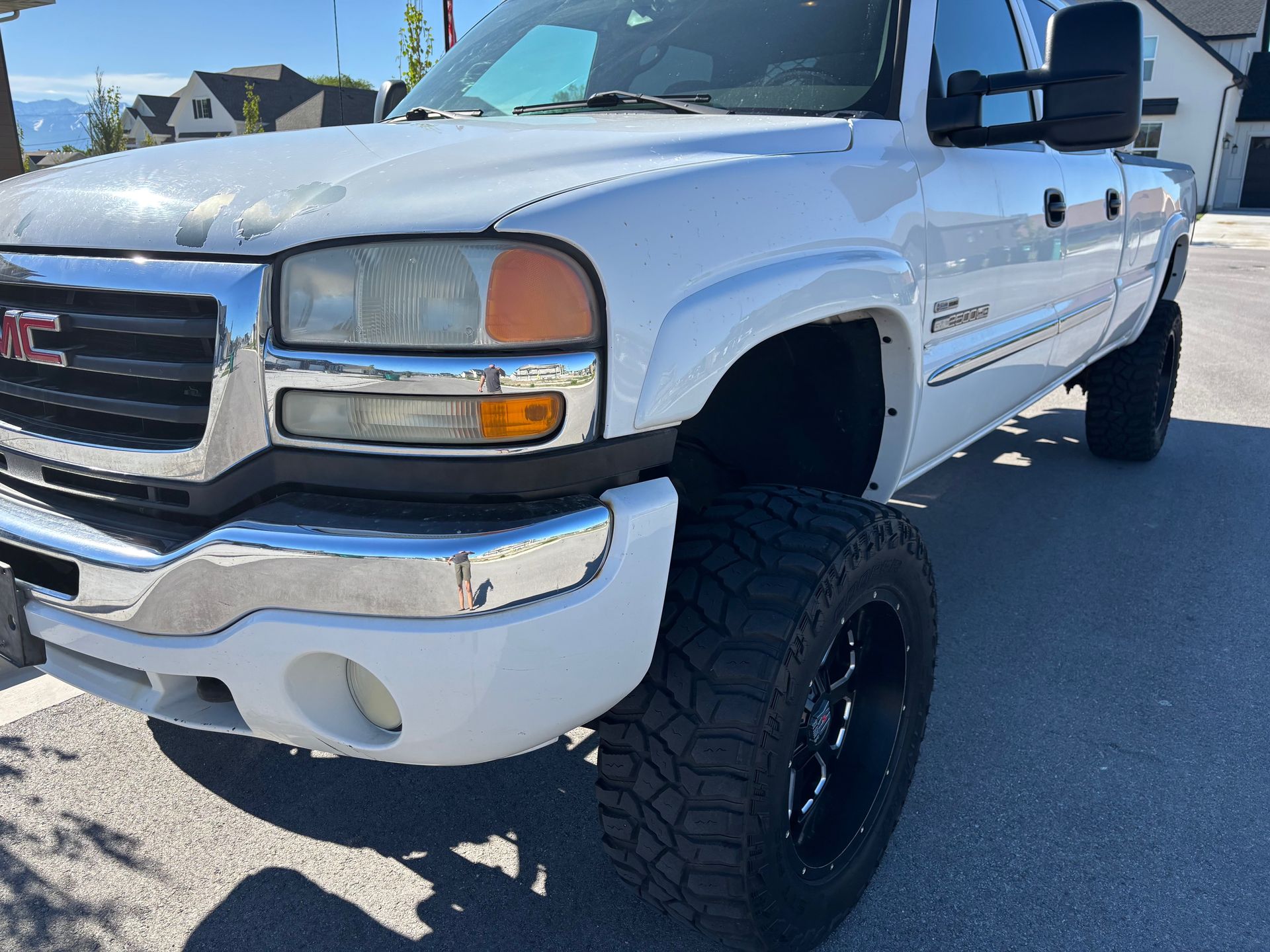 A white gmc truck is parked on the side of the road.