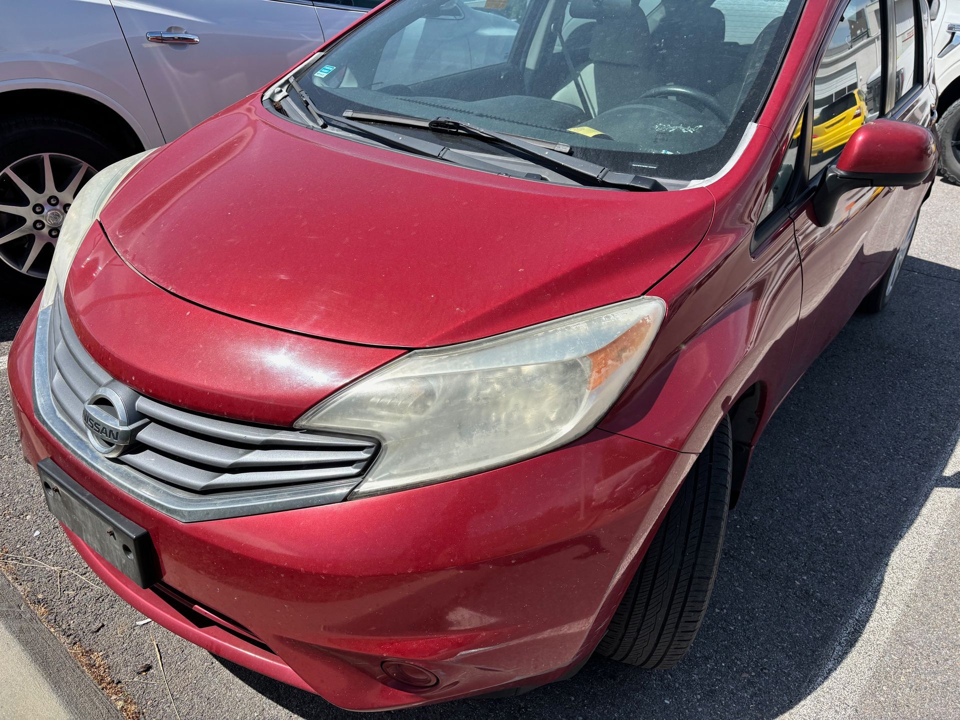 A red car is parked on the side of the road next to a white car.