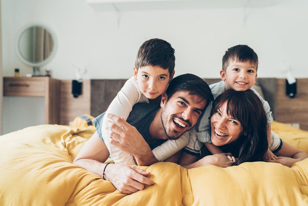 Smiling Family Lying On The Bed — Aurora, CO — Katherine Moskal Health Plans