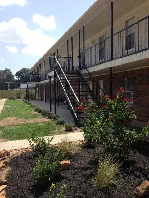 Exterior of apartment building with metal stairs, balconies, and landscaped walkway