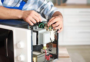 Worker Repairing Microwave — Coastal Test & Tag in Bonville, NSW
