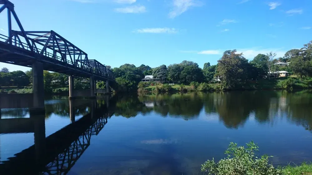 A Dark Metal Truss Bridge Crossing a Calm River — Mid North Coast Heavy Vehicle Repairs In Kempsey, NSW