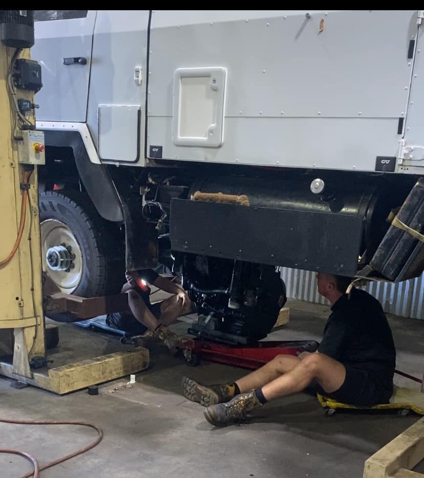 A Technician Works Underneath the Chassis of a Large White Truck — Mid North Coast Heavy Vehicle Repairs In Wauchope, NSW