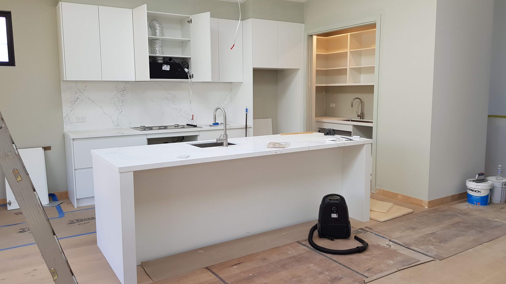 Modern Kitchen Under Construction With White Cabinets, Island, and Unfinished Floors — Canelo Cabinetry In Rocklea, QLD