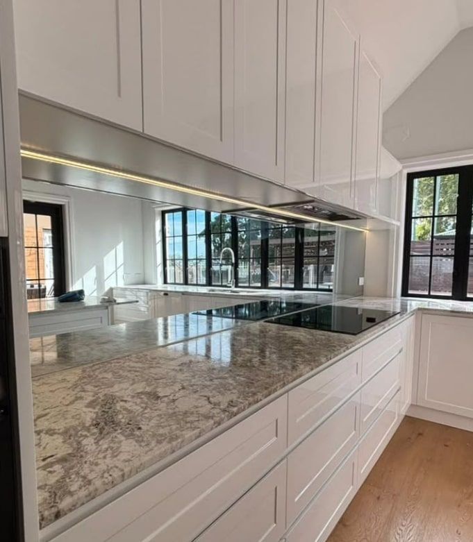Modern White Kitchen With Large Island, Granite Countertop, and Reflective Backsplash — Canelo Cabinetry In Rocklea, QLD