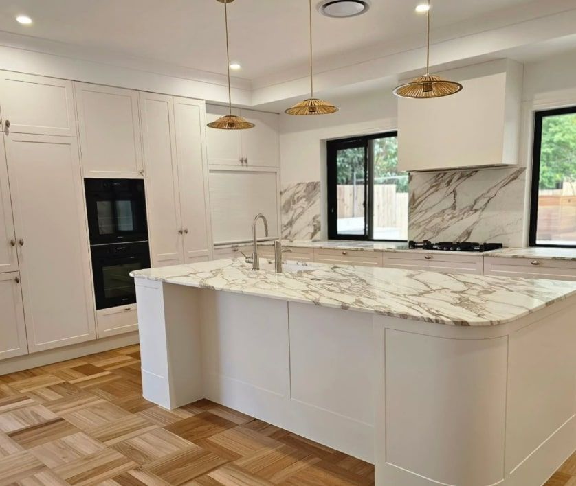 White Modern Kitchen With Marble Countertops, Gold Fixtures, and Wood Floor — Canelo Cabinetry In Rocklea, QLD