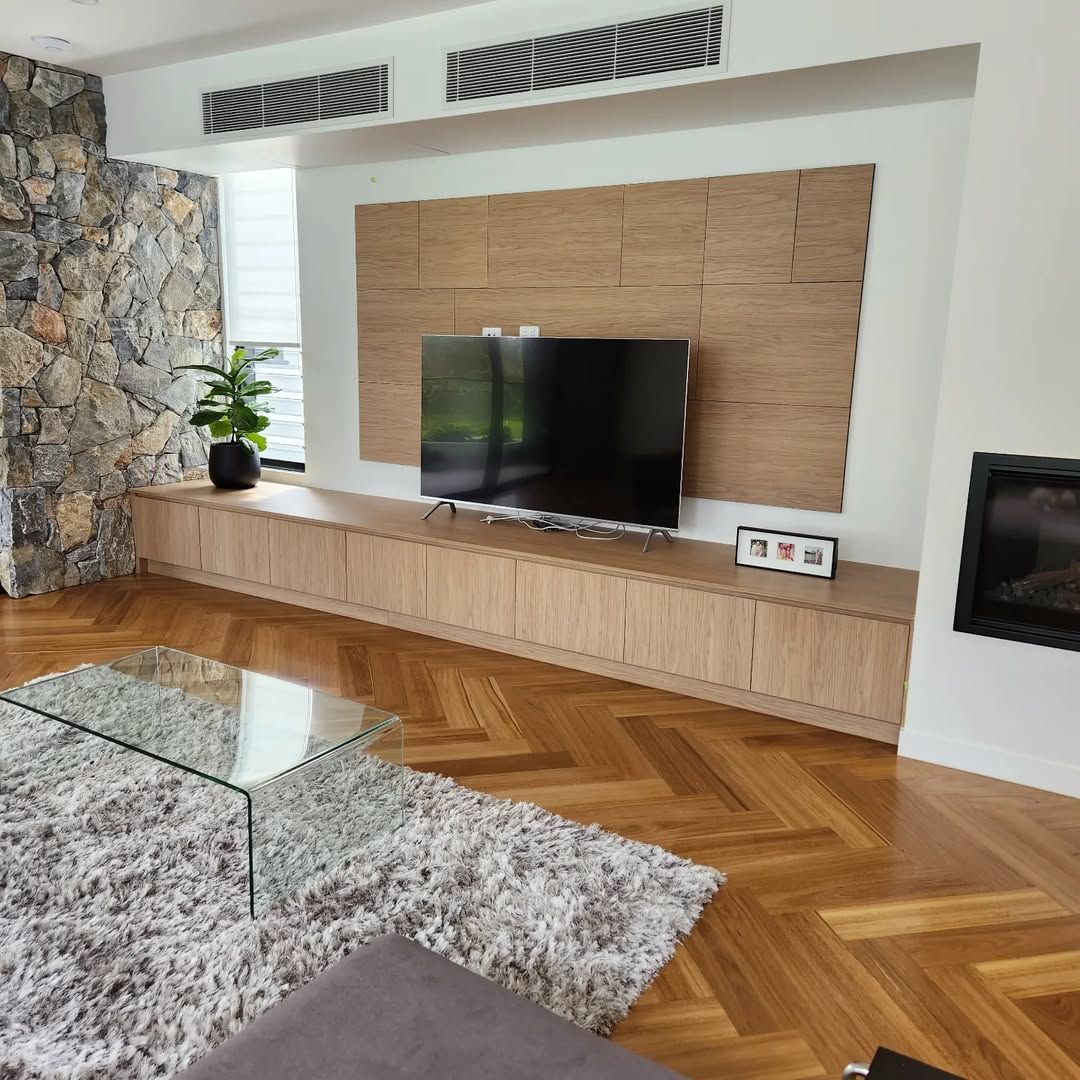 Living Room With Wooden Floors, Built-in Cabinetry, TV, and a Stone Wall — Canelo Cabinetry In Rocklea, QLD