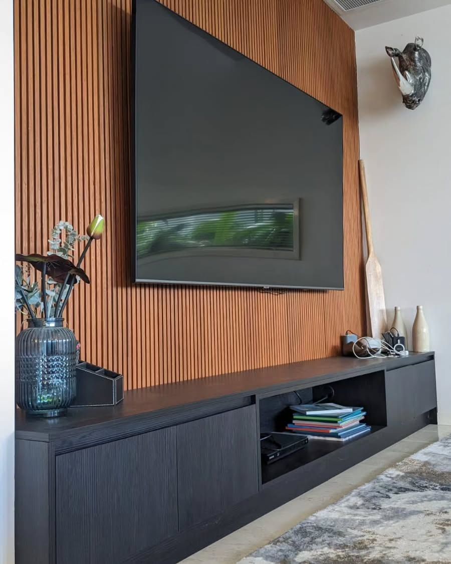 Black TV Mounted on a Wood Panelled Wall Above a Black Console With Decorations — Canelo Cabinetry In Rocklea, QLD