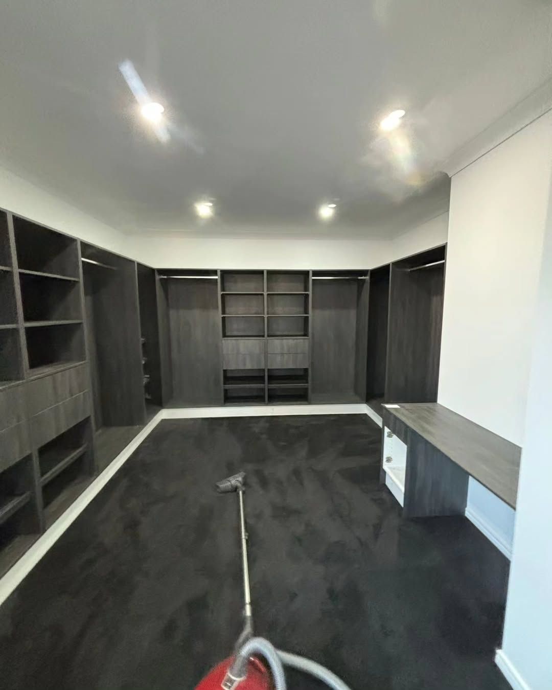 Walk-in Closet With Dark Cabinets, Grey Carpet, and a Vacuum Cleaner — Canelo Cabinetry In Rocklea, QLD