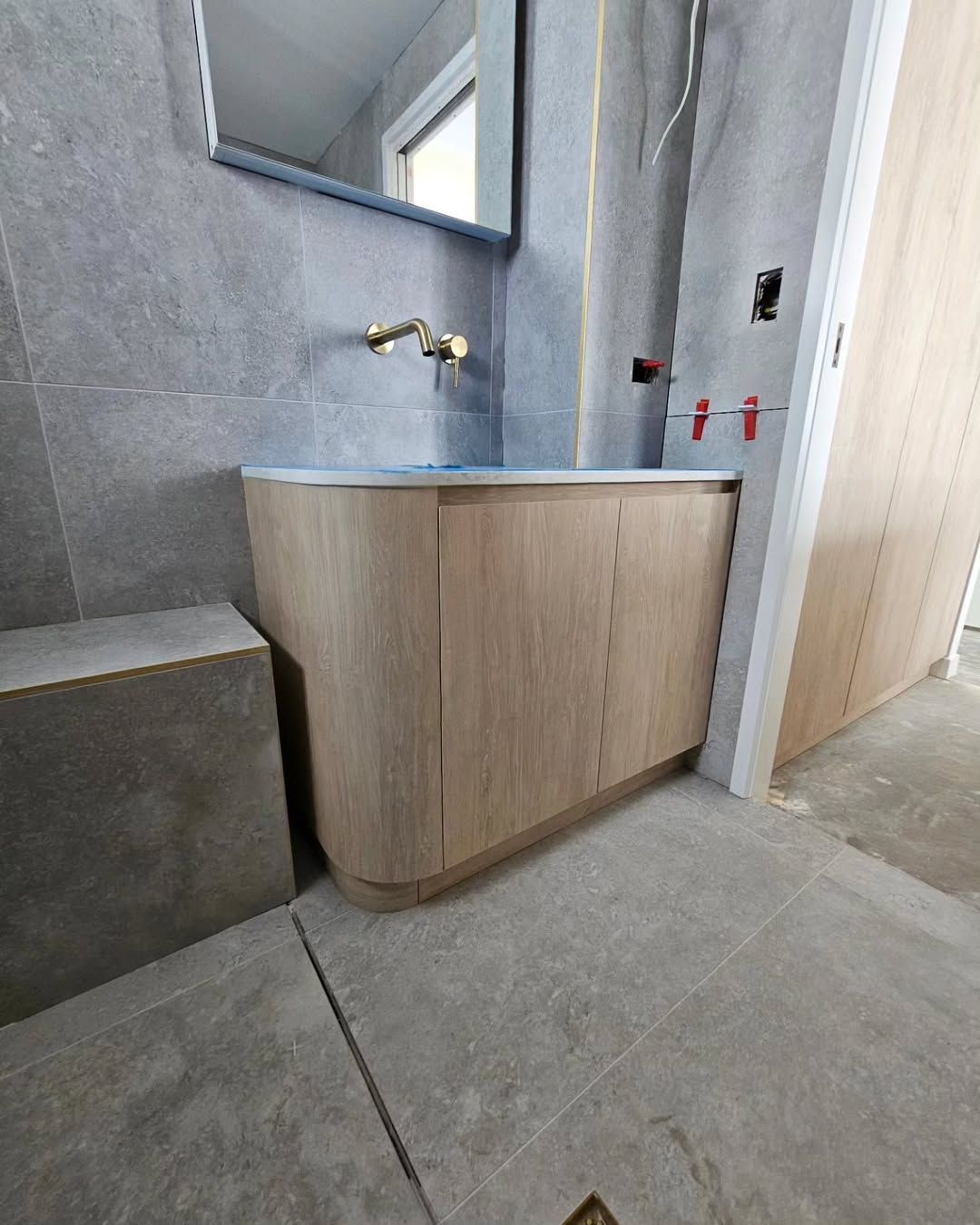 Bathroom With Wooden Cabinet, Gold Fixtures, Grey Tile, and Rectangular Mirror — Canelo Cabinetry In Rocklea, QLD