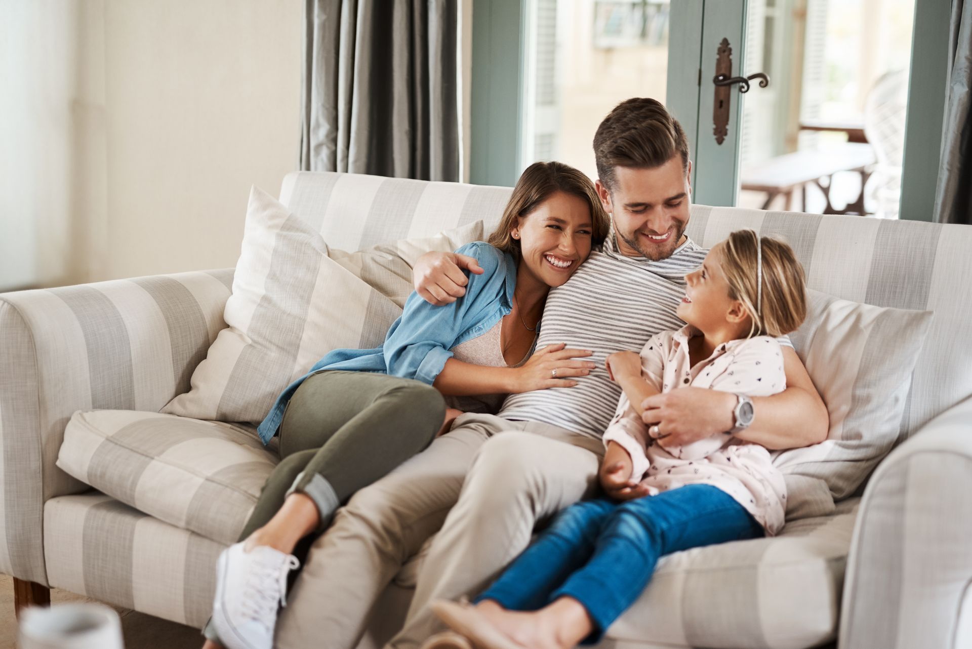 Family on a couch, smiling and hugging, in a living room.