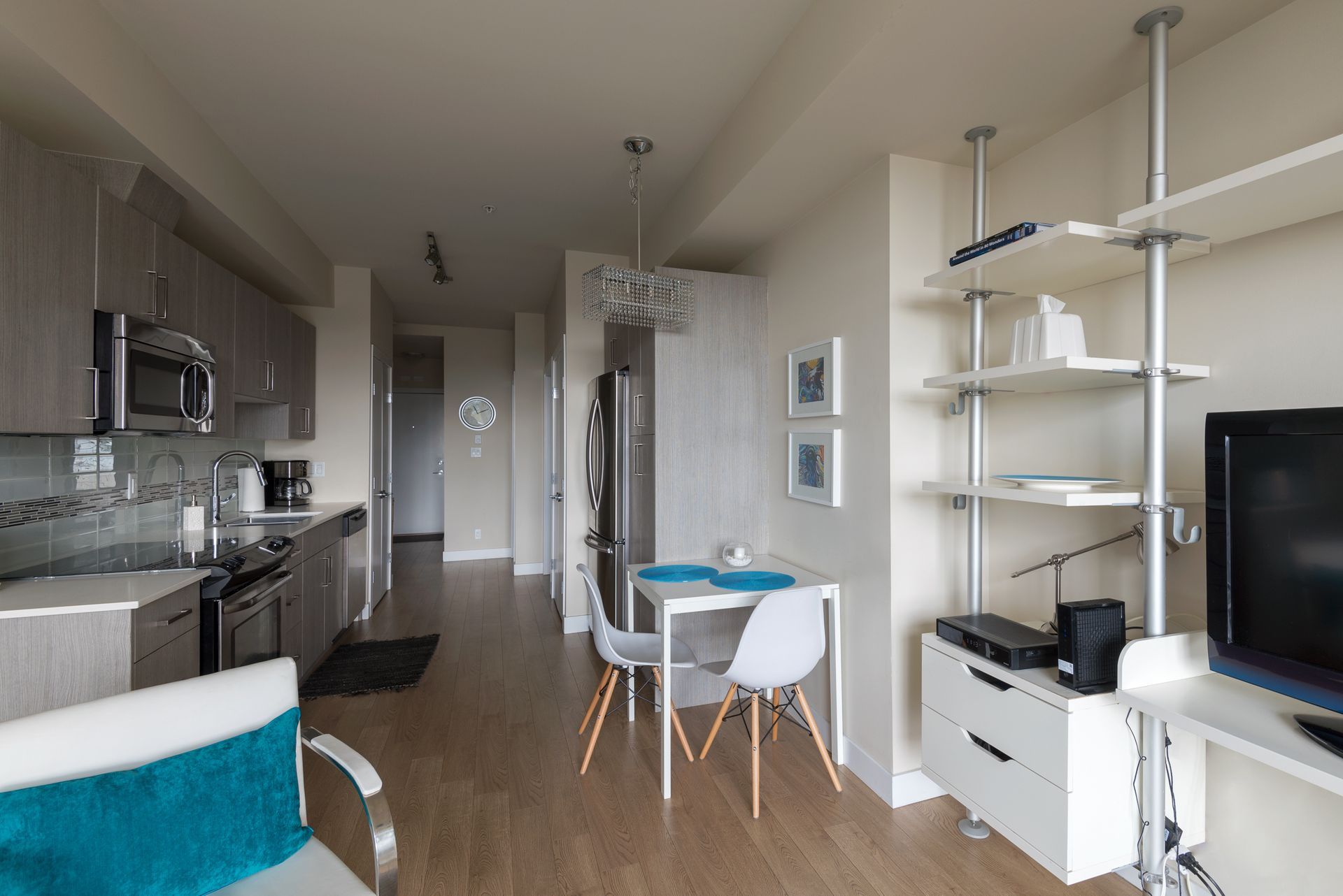 Modern apartment interior with kitchen, dining area, and living space; neutral colors, wood flooring.