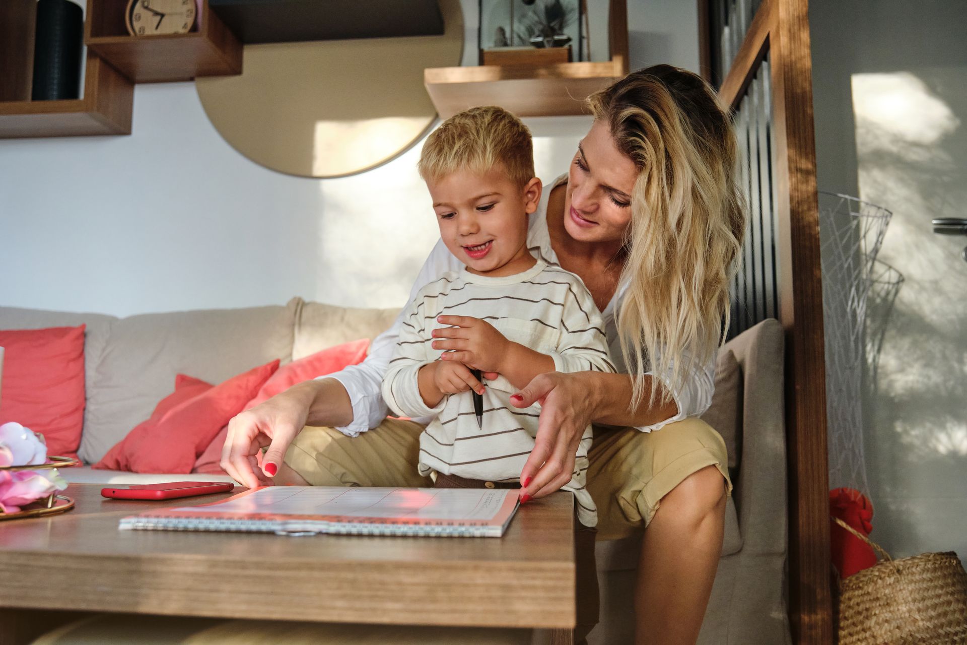 Woman and child sitting together at a coffee table, looking at a book.