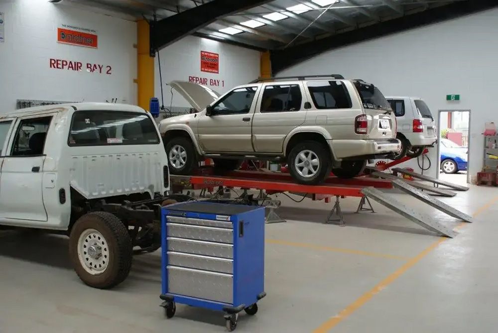 Two Cars Are Sitting On A Lift In A Garage — Atherton Smash Repair Specialist in Atherton, QLD