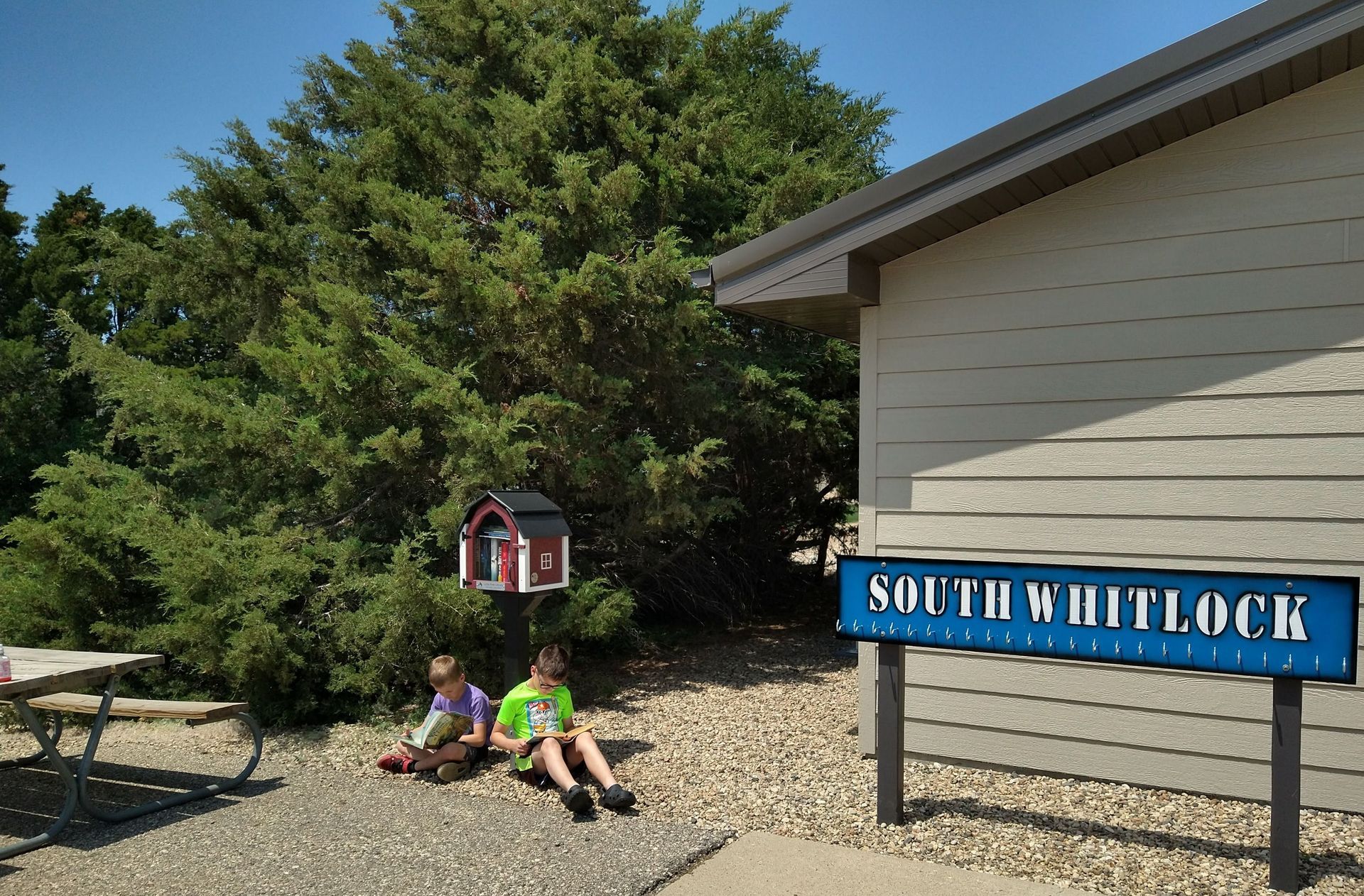 Two children sit on the ground in front of a building that says south whitlock