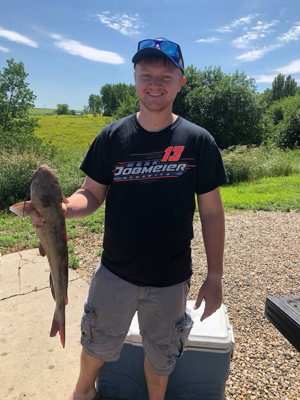 A man in a black shirt is holding a large fish.