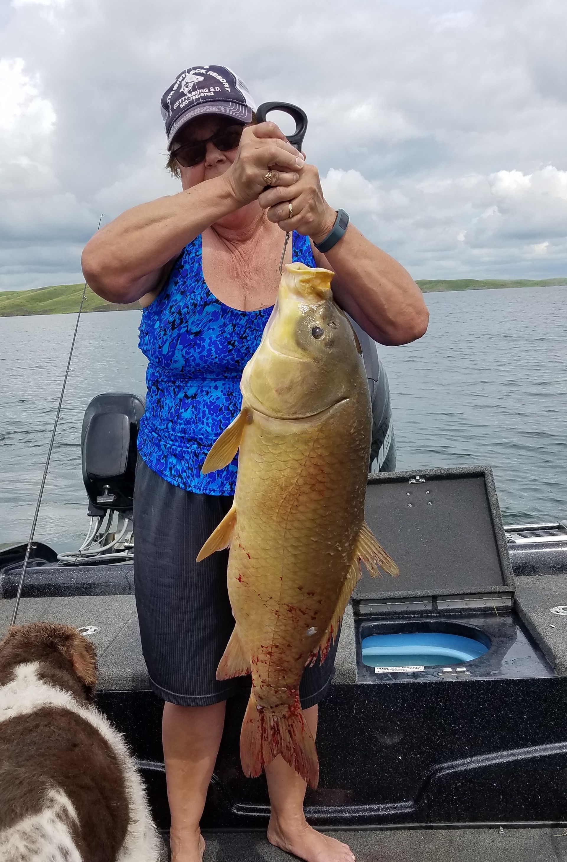 A woman is holding a large fish on a boat.