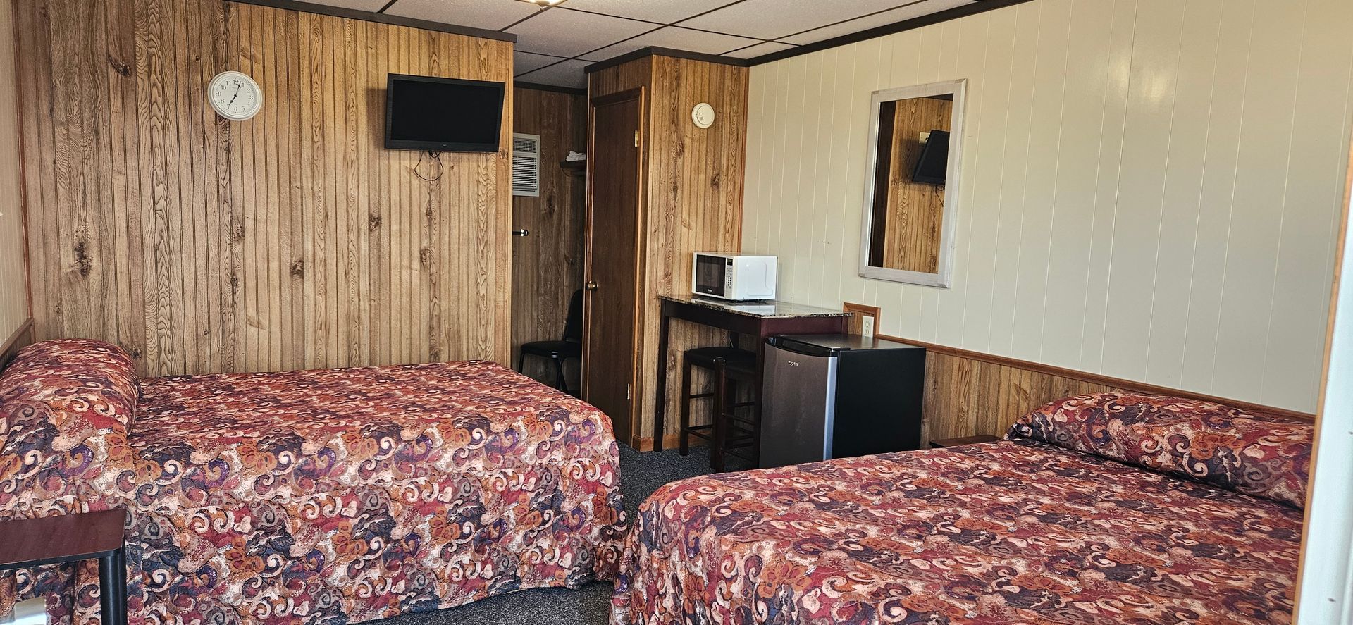 A hotel room with two beds , a desk and a television.