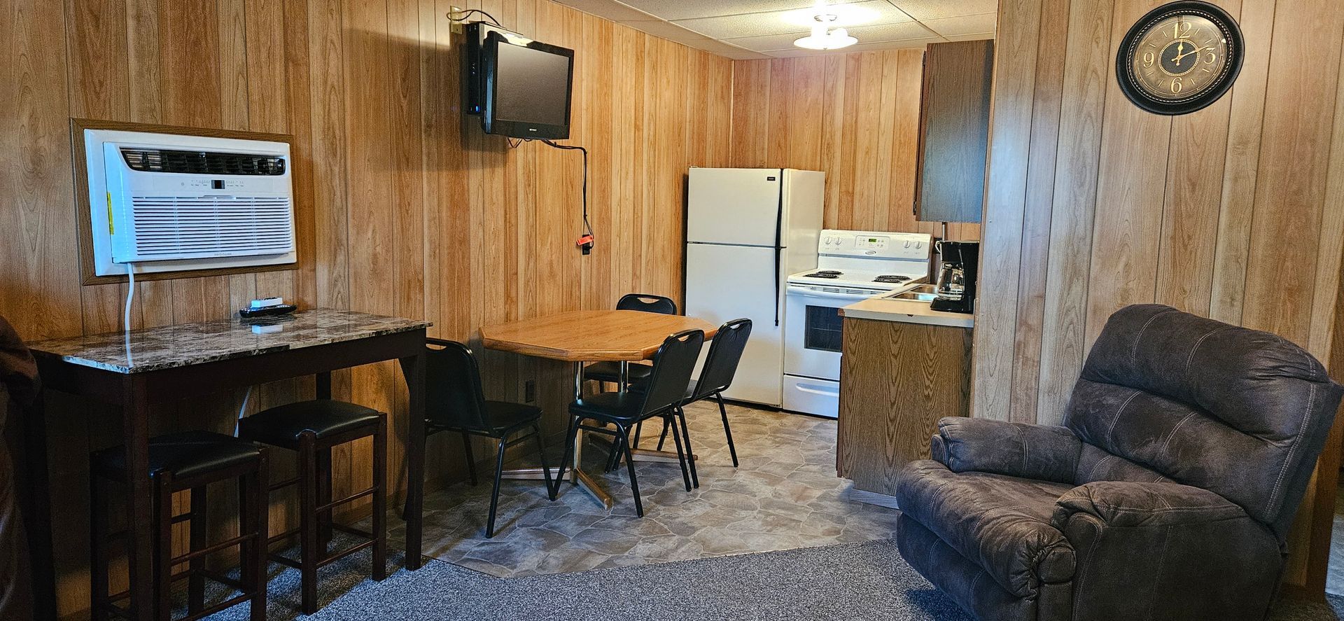 A living room with a table , chairs , refrigerator and television.