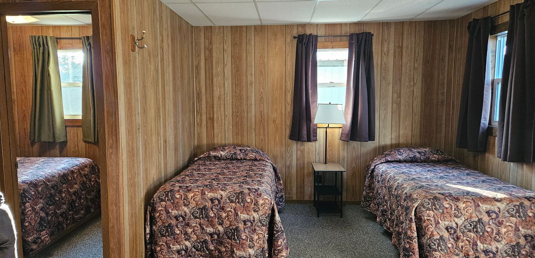 A bedroom with two beds and a mirror.