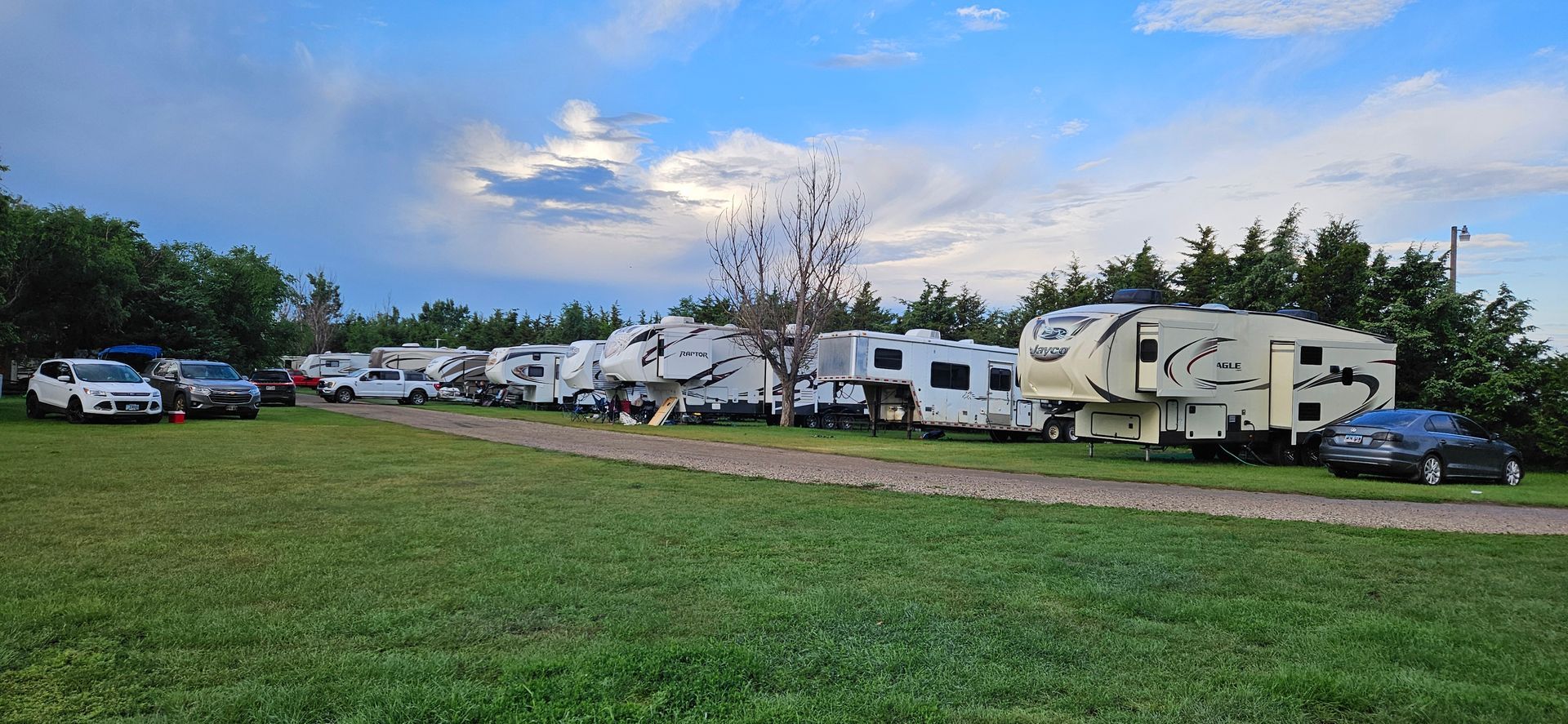 A row of rvs are parked in a grassy field.