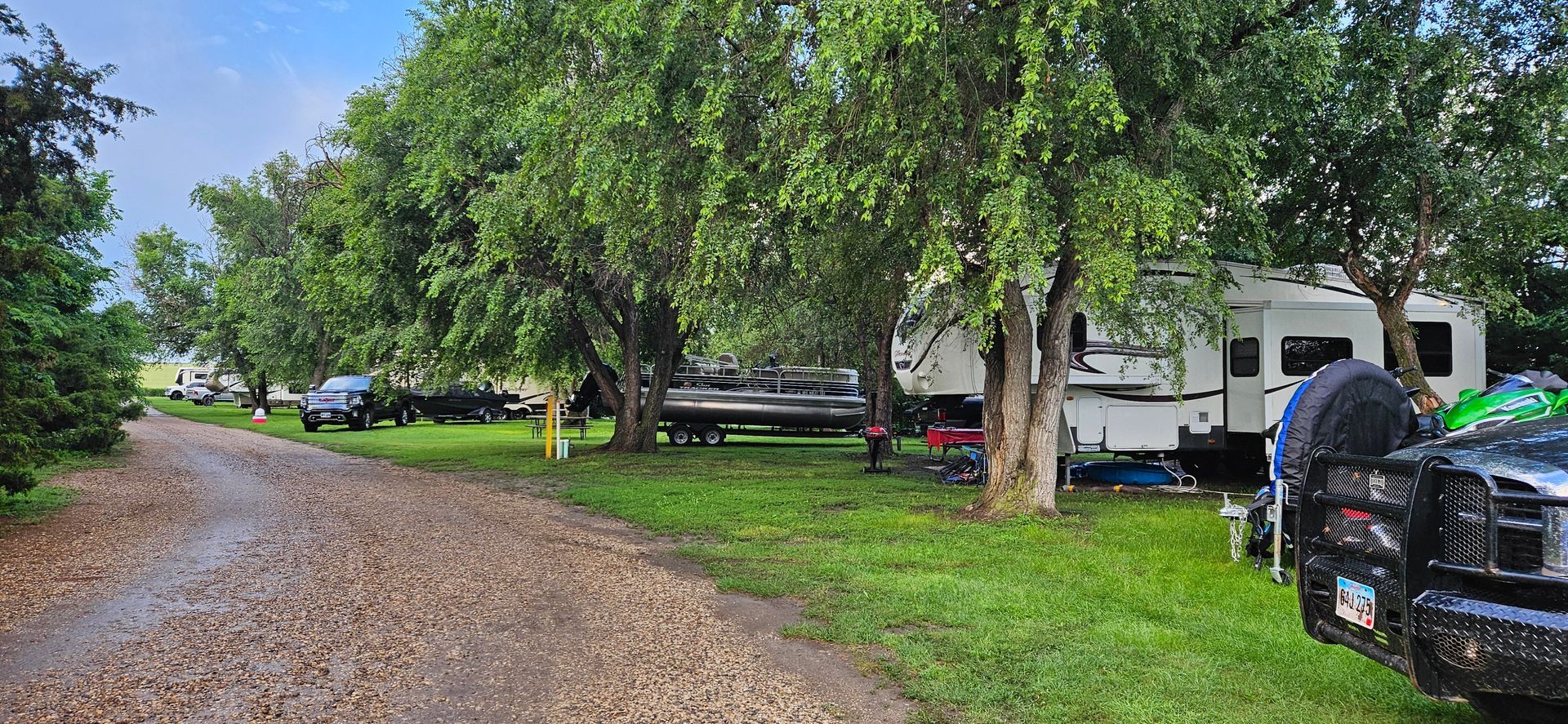 A dirt road leading to a rv park surrounded by trees.