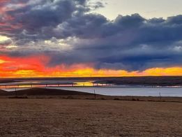 A sunset over a body of water with a bridge in the distance.