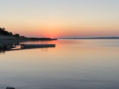 A sunset over a body of water with a dock in the foreground.