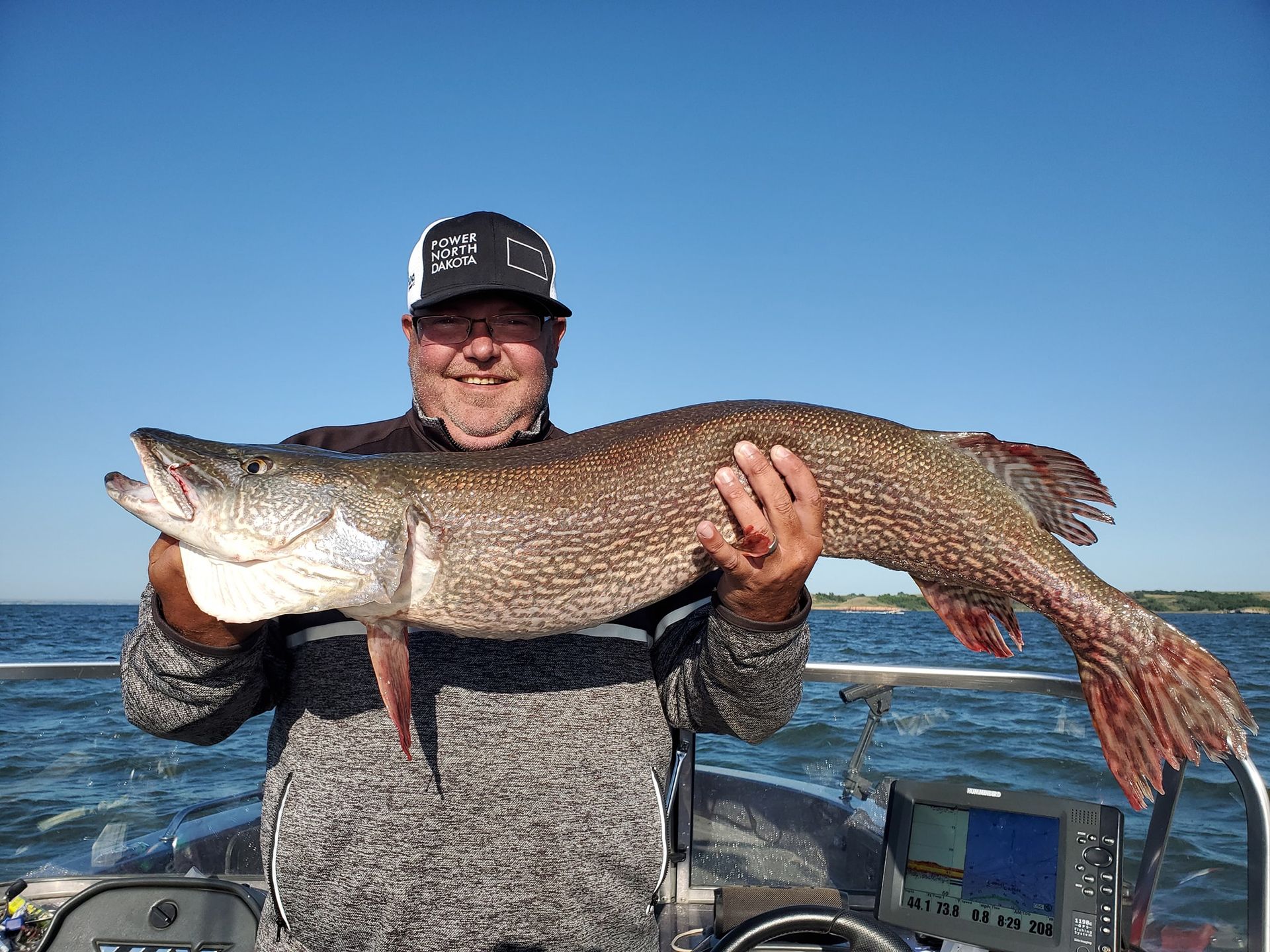 A man is holding a large fish on a boat.